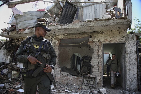 A police officer stands guard outside a home that was destroyed by a car bomb that exploded near a police station in a rural area of Jamundi, Colombia, Friday, Sept. 22, 2023. (AP Photo/Andres Quintero)