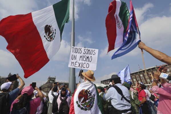 A person holds a sign that reads "we are all the same Mexico" at an opposition rally called to encourage voting ahead of the June 2 presidential elections, in the Zocalo, Mexico City's main square, Sunday, May 19, 2024. (AP Photo/Ginnette Riquelme)