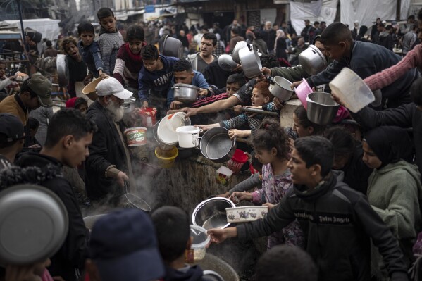Palestinians line up for a meal in Rafah, Gaza Strip, Thursday, Dec. 21, 2023. International aid agencies say Gaza is suffering from shortages of food, medicine and other basic supplies as a result of the two and a half month war between Israel and Hamas. (AP Photo/Fatima Shbair)