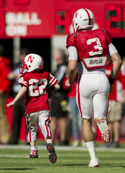 Nebraska's Taylor Martinez (3) guides Jack Hoffman, then 6, of Atkinson, Neb., down the field for his touchdown play during a special segment dedicated to Hoffman during the second half of the Red-White spring NCAA college football game at Memorial Stadium in Lincoln, Ne., April 6, 2013. (AP Photo/Lincoln Journal Star, Matt Ryerson, File)