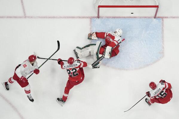 Russian Olympic Committee's Pavel Karnaukhov (15) scores a goal against Denmark goalkeeper Frederik Dichow (1) during a preliminary round men's hockey game at the 2022 Winter Olympics, Friday, Feb. 11, 2022, in Beijing. (AP Photo/Matt Slocum)