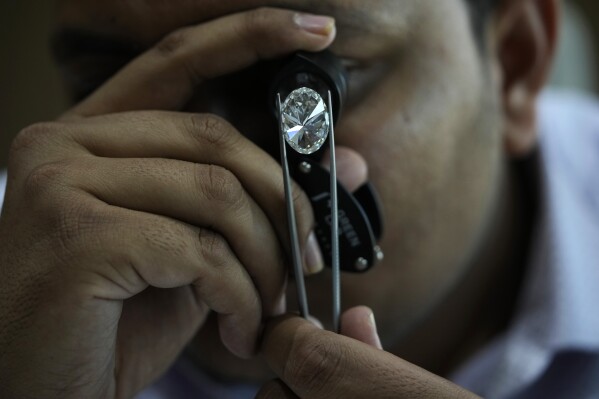 A man looks at a polished lab-grown diamond at Greenlab Diamonds, in Surat, India, Monday, Feb. 5, 2024. Diamonds, whether lab grown or natural, are chemically identical and entirely made out of carbon. (AP Photo/Ajit Solanki)