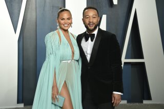 FILE - This Feb. 9, 2020 file photo, Chrissy Teigen, left, and John Legend arrive at the Vanity Fair Oscar Party in Beverly Hills, Calif.   Teigen and Legend have revealed the “deep pain” they are feeling, over the loss of their unborn baby following pregnancy complications. Teigen announced their loss on her social media accounts early Thursday, Sept. 30, saying they were "driving home from the hospital with no baby. This is unreal."  (Photo by Evan Agostini/Invision/AP, File)