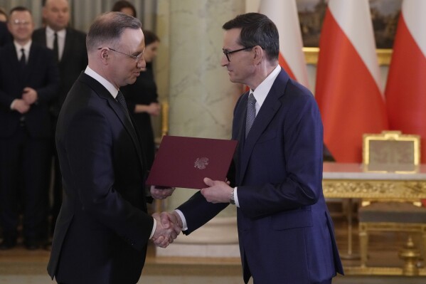 Poland's President Andrzej Duda, left, shakes hands with Prime Minister Mateusz Morawiecki, during a swearing-in ceremony in Warsaw, Poland, Monday Nov. 27, 2023. Duda swore in a government that is expected to last no longer than 14 days, a tactical manever that allows the conservative Law and Justice party to hang onto power a bit longer — and make more appointments to state bodies. (AP Photo/Czarek Sokolowski)