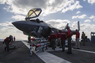Marine Wing Fighter Attack Squadron (VMFA) 314 personnel refuel and load an F-35C Lightning II with the AIM-120 advanced medium-range air-to-air missile as VMFA-314 performs simulated offensive and defensive air operations, as well as close air support training missions in support of Jungle Warfare Exercise 22 (JWX 22) across Okinawa, Japan on Feb. 15, 2022. The U.S. Navy says it has recovered an F-35C Lightning II aircraft that crashed while attempting to land on an aircraft carrier in the South China Sea in January. (Capt. Charles Allen/U.S. Navy via AP)
