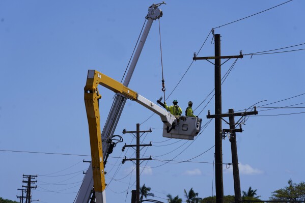 FILE - Linemen work on poles, Aug. 13, 2023, in Lahaina, Hawaii, following a deadly wildfire. Hawaii’s electric utility acknowledged its power lines started a wildfire on Maui but faulted county firefighters for declaring the blaze contained and leaving the scene, only to have a second wildfire break out nearby and become the deadliest in the U.S. in more than a century. (AP Photo/Rick Bowmer, File)