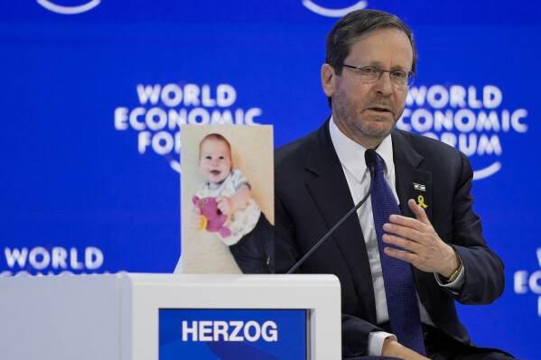Israel's President Isaac Herzog speaks at the World Economic Forum in Davos, Switzerland, Thursday, Jan. 18, 2024. The picture next to President Isaac Herzog shows a baby taken hostage by Hamas during the Oct. 7 cross-border attack in Israel. The annual meeting of the World Economic Forum is taking place in Davos from Jan. 15 until Jan. 19, 2024. (AP Photo/Markus Schreiber)