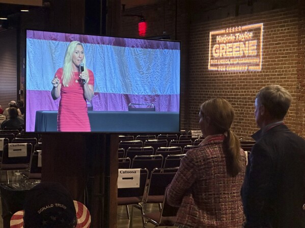 Two attendees at the Georgia State Republican Party Convention watch U.S. Rep. Marjorie Taylor Greene, R-Ga., speak to delegates on Saturday, May 18, 2024, in Columbus, Ga. (AP Photo/Jeff Amy)