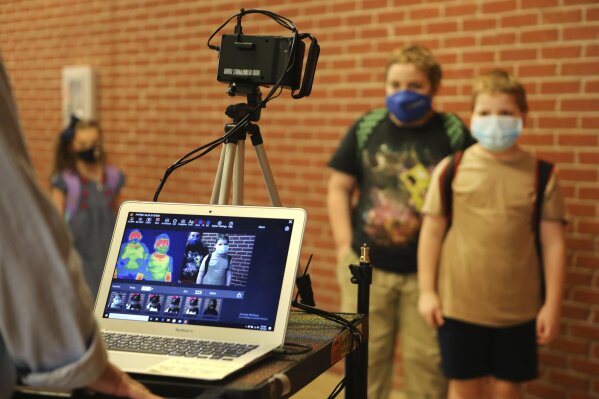 Corinth Elementary School students have their temperature checked by a thermal scanner as they arrive for their first day back to school Monday, July 27, 2020 in Corinth, Miss. (Adam Robison/The Northeast Mississippi Daily Journal via AP)