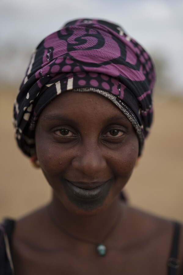Houraye Ndiaye, 20, stands for a portrait in the village of Dendoudy Dow, in the Matam region of Senegal, Monday, April 17, 2023. Ndiaye travels with her husband and their two-year-old girl, along with her parents and two other siblings. She says that moving the livestock has its benefits but there are many difficulties as well. As her husband, Moussa Ifra Ba, plans having three boys, she offered up a proposal. "One can raise the cattle, one can tend to the sheep and the third son can go to school". (AP Photo/Leo Correa)