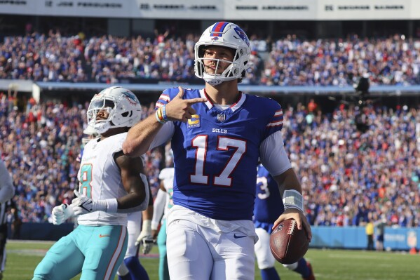 Buffalo Bills quarterback Josh Allen celebrates in the end zone in front of Miami Dolphins safety Jevon Holland, left, after scoring a touchdown in the second half an NFL football game, Sunday, Oct. 1, 2023, in Orchard Park, N.Y. (AP Photo/Jeffrey T. Barnes)