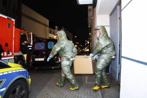 FILE - Men in protective suits carry a cardboard box out of a house in Castrop-Rauxel during an anti-terror operation on Jan. 8, 2023. An Iranian man arrested earlier this year after a tip from U.S. officials has been charged in Germany with plotting an Islamist attack using ricin or cyanide, prosecutors said Wednesday June 21, 2023. (7aktuell.de, Marc Gruber/dpa via AP, File)