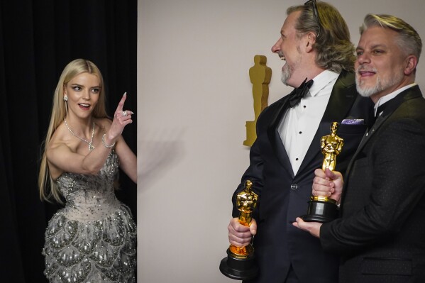 Dave Mullins, center, and Brad Booker, winners of the award for best animated short for "War Is Over! Inspired by the Music of John & Yoko," pose in the press room at the Oscars on Sunday, March 10, 2024, at the Dolby Theatre in Los Angeles. Anya Taylor-Joy, left, looks on. (Photo by Jordan Strauss/Invision/AP)