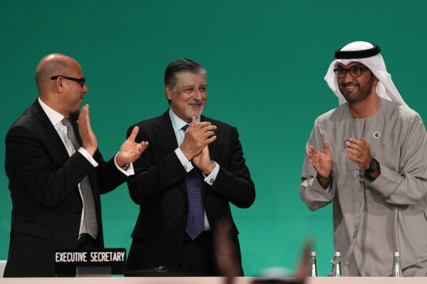 COP28 President Sultan al-Jaber, right, celebrates passing the global stocktake with United Nations Climate Chief Simon Stiell, left, and COP28 CEO Adnan Amin during a plenary session at the COP28 U.N. Climate Summit, Wednesday, Dec. 13, 2023, in Dubai, United Arab Emirates. (AP Photo/Kamran Jebreili)