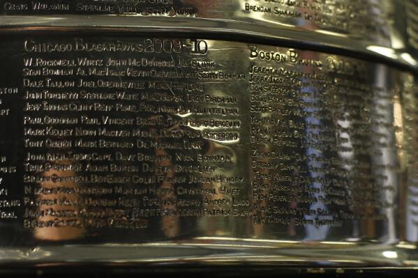 FILE - The names of the 2010 Stanley Cup Champion Chicago Blackhawks, left, are displayed on the Stanley Cup in the lobby of the United Center during an NHL hockey news conference on June 11, 2013 in Chicago. The first game of the Stanley Cup final series is Wednesday in Chicago. Blackhawks owner Rocky Wirtz wants the Hockey Hall of Fame to cover the name of an assistant coach engraved on the Stanley Cup after the assistant was accused of sexually assaulting a player during the team's run to the 2010 championship. (AP Photo/Charles Rex Arbogast, File)