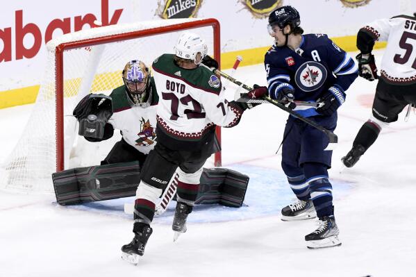 Arizona Coyotes goaltender Karel Vejmelka, left, makes a save against a Winnipeg Jets shot as Coyotes center Travis Boyd (72) and Jets center Mark Scheifele (55) battle in front of the net during first-period NHL hockey game action in Winnipeg, Manitoba, Sunday, Jan. 15, 2023. (Fred Greenslade/The Canadian Press via AP)