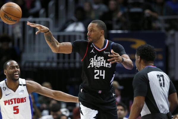 Los Angeles Clippers forward Norman Powell (24) passes the ball against Detroit Pistons guard Alec Burks (5) with referee Mitchell Ervin (27) watching the action during the first half of an NBA basketball game, Monday, Dec. 26, 2022, in Detroit. (AP Photo/Duane Burleson)