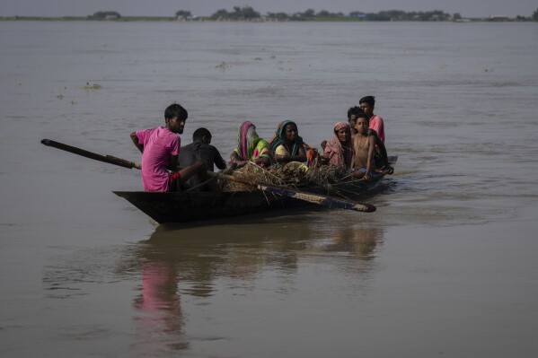 Villagers on a boat leave their submerged house in Sandahkhaiti, a floating island village in the Brahmaputra River in Morigaon district, Assam, India, Tuesday, Aug. 29, 2023. (AP Photo/Anupam Nath)
