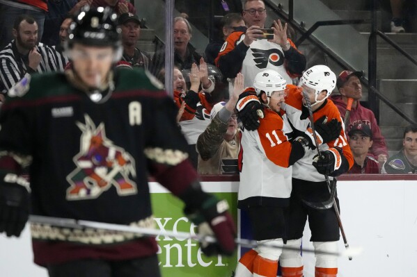 Philadelphia Flyers right wing Travis Konecny (11) celebrates after his goal against the Arizona Coyotes with Flyers center Scott Laughton (21) as Coyotes right wing Clayton Keller, left, pauses on the ice during the second period of an NHL hockey game Thursday, Dec. 7, 2023, in Tempe, Ariz. (AP Photo/Ross D. Franklin)
