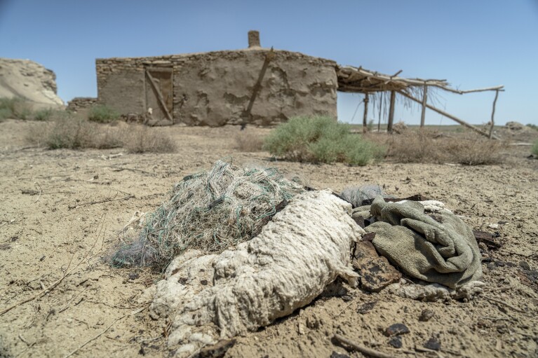 A worn-out fishing net sits next to an abandoned building by the dried-up Aral Sea, near Muynak, Uzbekistan, Saturday, June 24, 2023. (AP Photo/Ebrahim Noroozi)