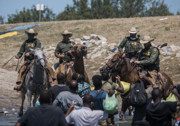U.S. Customs and Border Protection mounted officers attempt to contain migrants as they cross the Rio Grande from Ciudad Acuña, Mexico, into Del Rio, Texas, Sunday, Sept. 19, 2021. Thousands of Haitian migrants have been arriving to Del Rio, Texas, as authorities attempt to close the border to stop the flow of migrants. (AP Photo/Felix Marquez)