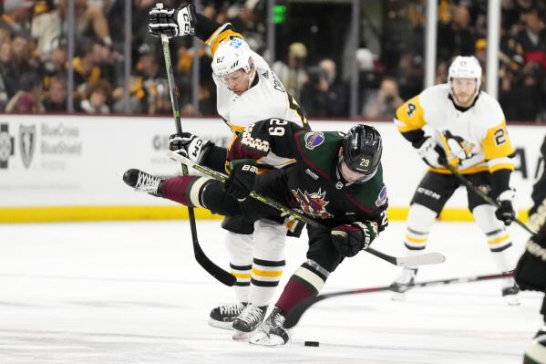 Pittsburgh Penguins center Sidney Crosby sends Arizona Coyotes center Barrett Hayton (29) to the ice as Penguins defenseman Ty Smith looks on during the second period of an NHL hockey game in Tempe, Ariz., Sunday, Jan. 8, 2023. (AP Photo/Ross D. Franklin)