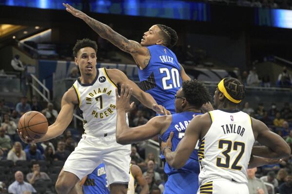 Indiana Pacers guard Malcolm Brogdon (7) looks to pass the ball to guard Terry Taylor (32) as Orlando Magic guard Markelle Fultz (20) and center Wendell Carter Jr. defend during the first half of an NBA basketball game Wednesday, March 2, 2022, in Orlando, Fla. (AP Photo/Phelan M. Ebenhack)