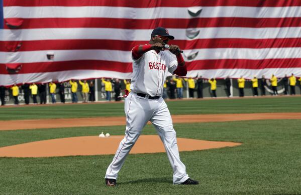FILE - Boston Red Sox's David Ortiz pumps his fist in front of a United States flag and a line of Boston Marathon volunteers, background, after addressing the crowd before a baseball game between the Red Sox and the Kansas City Royals in Boston, April 20, 2013. Ortiz says he knows the speech he gave at the first game at Fenway Park after the Boston Marathon bombing had an impact in Boston and around the world. (AP Photo/Michael Dwyer, File)