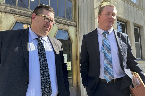 North Dakota Republican state Rep. Jason Dockter, left, and his attorney, Lloyd Suhr, meet with others on the steps of the Burleigh County Courthouse in Bismarck, N.D., Thursday, May 9, 2024, after Dockter was sentenced to serve 250 hours of community service and pay a $2,500 fine after a jury convicted him of a misdemeanor in connection with a controversial state-leased building he has an ownership in. (AP Photo/Jack Dura)