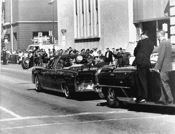 Secret servicemen standing on running boards follow the presidential limousine carrying President John F. Kennedy, right, rear seat, and first lady Jacqueline Kennedy, left, as well as Texas Gov. John Connally and his wife, Nellie, in Dallas, Texas, Nov. 22, 1963. (AP Photo/Jim Altgens, File)