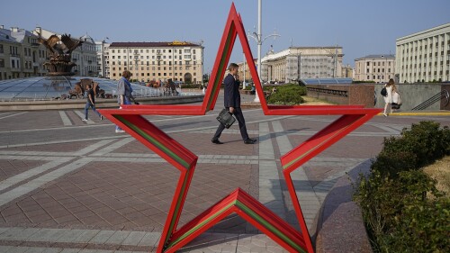 People walk in Independent Square during sunset in Minsk, Belarus, Wednesday, July 5, 2023. (AP Photo/Alexander Zemlianichenko)