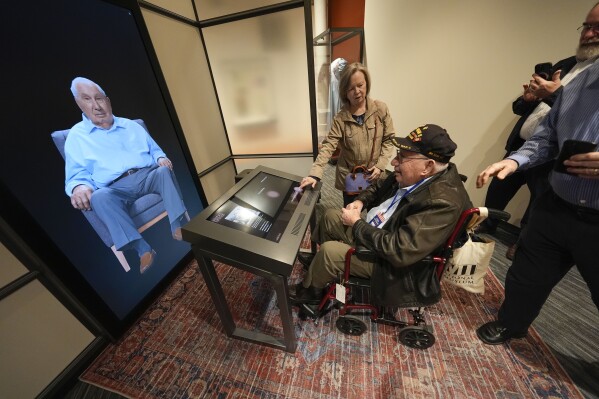 World War II veteran Olin Pickens, of Nesbit, Miss., who served in the U.S. Army 805th Tank Destroyer Battalion, looks at the virtual exhibit of himself at the National World War II Museum in New Orleans, Wednesday, March 20, 2024. An interactive exhibit opening Wednesday at the museum will use artificial intelligence to let visitors hold virtual conversations with images of veterans, including a Medal of Honor winner who died in 2022. (AP Photo/Gerald Herbert)