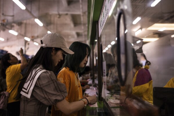 Visitors collect their money after betting at the Macao Jockey Club in Macao, Saturday, March 30, 2024. After more than 40 years, Macao’s horse racing track hosted its final races on Saturday, bringing an end to the sport in the city famous for its massive casinos. (AP Photo/Louise Delmotte)