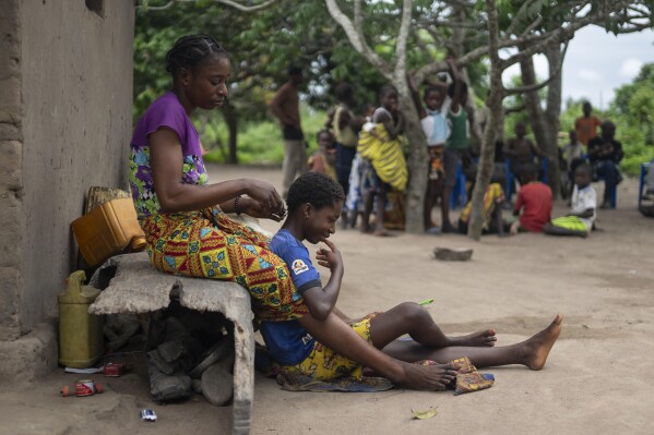 A mother braids her daughter's hair in Kimpozia village, one of the areas auctioned for oil drilling, in Moanda, Democratic Republic of the Congo, Monday, Dec. 25, 2023. Its government is auctioning off 30 oil and gas blocks around the country. (AP Photo/Mosa'ab Elshamy)
