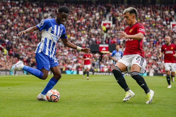 Brighton's Simon Adingra, left, dribbles the ball against Manchester United's Lisandro Martinez during the English Premier League soccer match between Manchester United and Brighton and Hove Albion at Old Trafford stadium in Manchester, England, Saturday, Sept. 16, 2023. (AP Photo/Dave Thompson)