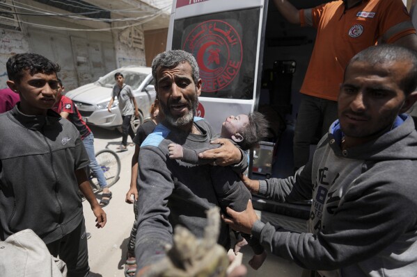 EDS NOTE: GRAPHIC CONTENT - Palestinians hold the body of a dead baby rescued from the rubble of a building destroyed in an Israeli airstrike in Nuseirat, Gaza Strip, Tuesday, May 14, 2024. (AP Photo/Abdel Kareem Hana)
