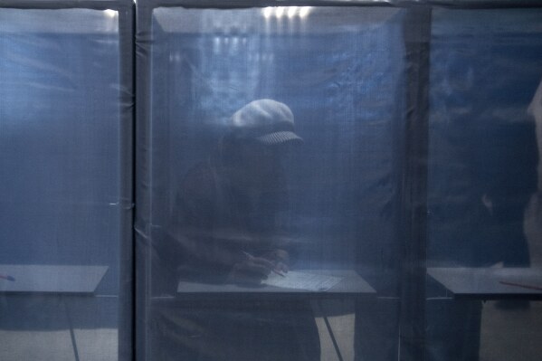 A woman fills in a ballot at a polling station during a presidential election in Russian-controlled Donetsk region of eastern Ukraine, Friday, March 15, 2024. People in Moscow-controlled Ukrainian regions voted in Russia's presidential election, which was all but certain to extend President Vladimir Putin's rule after he clamped down on dissent. (AP Photo)