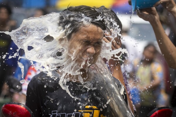 A man reacts as water is splashed on him during the Songkran water festival to celebrate the Thai New Year in Prachinburi Province, Saturday April 13, 2024. It's the time of year when many Southeast Asian countries hold nationwide water festivals to beat the seasonal heat, as celebrants splash friends, family and strangers alike in often raucous celebration to mark the traditional Theravada Buddhist New Year. (AP Photo/Wason Wanichakorn)