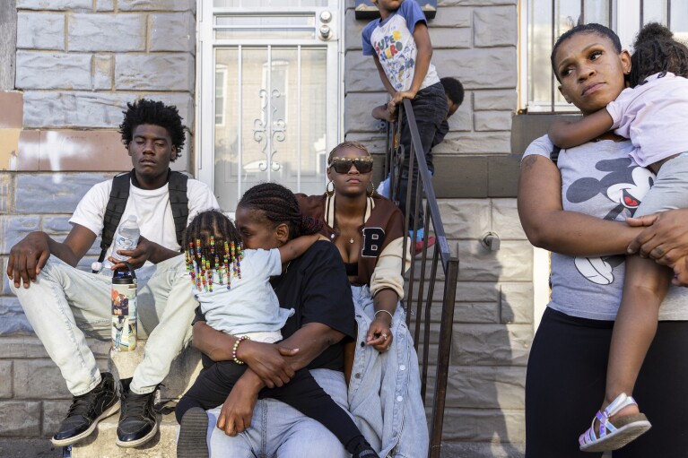 Friends and family comfort Antonio Lee's mother as she mourns her son at a vigil, Friday, Aug. 18, 2023, in Baltimore. Lee, 19, was shot and killed while squeegeeing in Baltimore. (AP Photo/Julia Nikhinson)