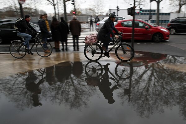 Bicycles riders are reflected in the water in Paris, Saturday, Dec. 7, 2019. French strikes are disrupting weekend travel around the country, as truckers blocked highways and most trains remained at a standstill because of worker anger at President Emmanuel Macron's policies as a mass movement against the government's plan to redesign the national retirement system entered a third day. (AP Photo/Francois Mori)
