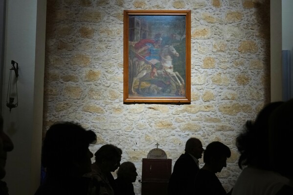 A painting of St. George hangs on the wall of St. George Church as the faithful attend a service, in the Maronite village of Kormakitis in the breakaway north of the ethnically divided Cyprus on Wednesday, April 23, 2025. (AP Photo/Petros Karadjias)