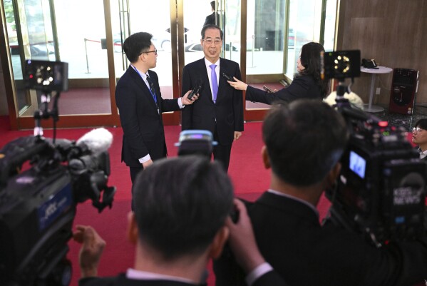South Korean Prime Minister Han Duck-soo, center, speaks to the media as he arrives at the Government Complex in Seoul Monday, March 24, 2025, after the Constitutional Court dismissed the impeachment of the prime minister. (Jung Yeon-je/Pool Photo via AP)
