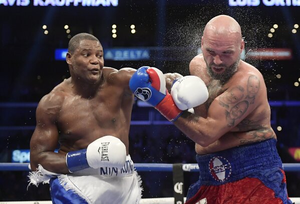
              FILE - In this Dec. 1, 2018, file photo, Luis Ortiz, left, hits Travis Kauffman with a knockdown punch during the sixth round of a heavyweight boxing match in Los Angeles. Ortiz and fellow boxing star Erislandy Lara left behind their lives in Cuba for the ones they wanted for themselves and their families in the United States. (AP Photo/Mark J. Terrill, File)
            