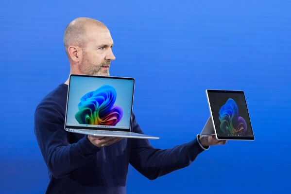 Brett Ostrum, Microsoft corporate vice president of Surface, holds up the new Surface Laptop and Surface Pro with built-in AI hardware during a showcase event of the company's AI assistant, Copilot, at Microsoft headquarters, Monday, May 20, 2024, in Redmond, Wash. (AP Photo/Lindsey Wasson)