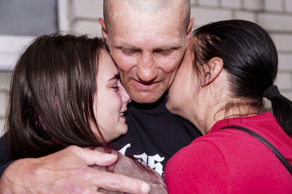 An Ukrainian soldier hugs with women after returning from captivity during a POWs exchange between Russia and Ukraine, in Chernyhiv region, Ukraine, Saturday, May 24, 2025. (AP Photo/Evgeniy Maloletka)