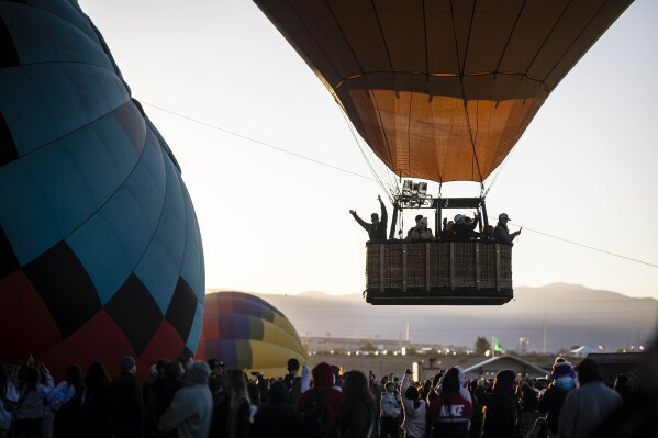 A balloon pilot waves to the crowd as he takes off during the Albuquerque International Balloon Fiesta, Saturday, Oct. 7, 2023 in Albuquerque, N.M. (AP Photo/Roberto E. Rosales)