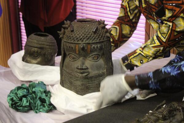 Benin bronzes looted in the past and returned to Nigeria are examined during a handing over ceremony in Abuja, Nigeria, Tuesday, Dec. 20, 2022. Germany returned 20 historic bronze sculptures to Nigeria as part of efforts to address what its foreign minister called its “dark colonial past.” Nigeria officials said that more than 5,000 ancient artifacts are estimated to have been stolen from Nigeria, the majority by England, the country’s former colonizer and some by Germany. (AP Photo/Olamikan Gbemiga)