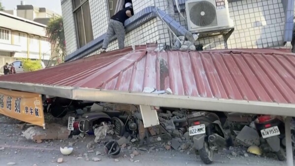 In this image taken from a video footage run by TVBS, a man checks a partially collapsed building in Hualien, eastern Taiwan on Wednesday, April 3, 2024. A powerful earthquake rocked the entire island of Taiwan early Wednesday, collapsing buildings in a southern city and creating a tsunami that washed ashore on southern Japanese islands.(TVBS via AP)