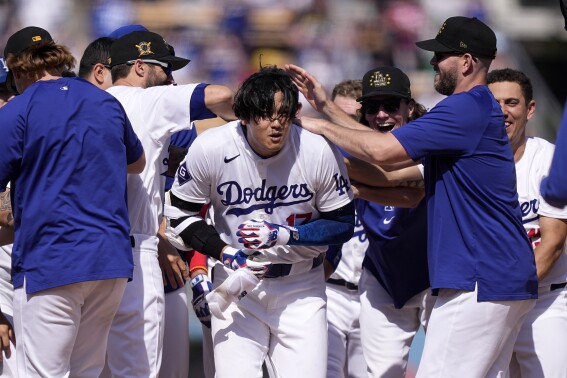 Los Angeles Dodgers' Shohei Ohtani, center, is congratulated by teammates after hitting a walk-off single during the 10th inning of a baseball game against the Cincinnati Reds Sunday, May 19, 2024, in Los Angeles. The Dodgers won 3-2. (AP Photo/Mark J. Terrill)
