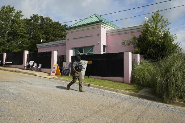 A security officer walks past the front of the Jackson Women's Health Organization clinic in Jackson, Miss., Sunday, July 3, 2022. The medical facility was open for three hours before anti-abortion protesters arrived. The clinic is the only facility that performs abortions in the state. On June 24, the U.S. Supreme Court overturned Roe v. Wade, ending constitutional protections for abortion. However, a Mississippi judge has set a hearing for Tuesday, in a lawsuit by the state's only abortion clinic that seeks to block a law that would ban most abortions. (AP Photo/Rogelio V. Solis)
